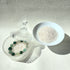 Crystal care essentials detail - bracelet resting on white quartz chips for energy purification