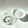 Crystal care essentials detail - bracelet resting on white quartz chips for energy purification