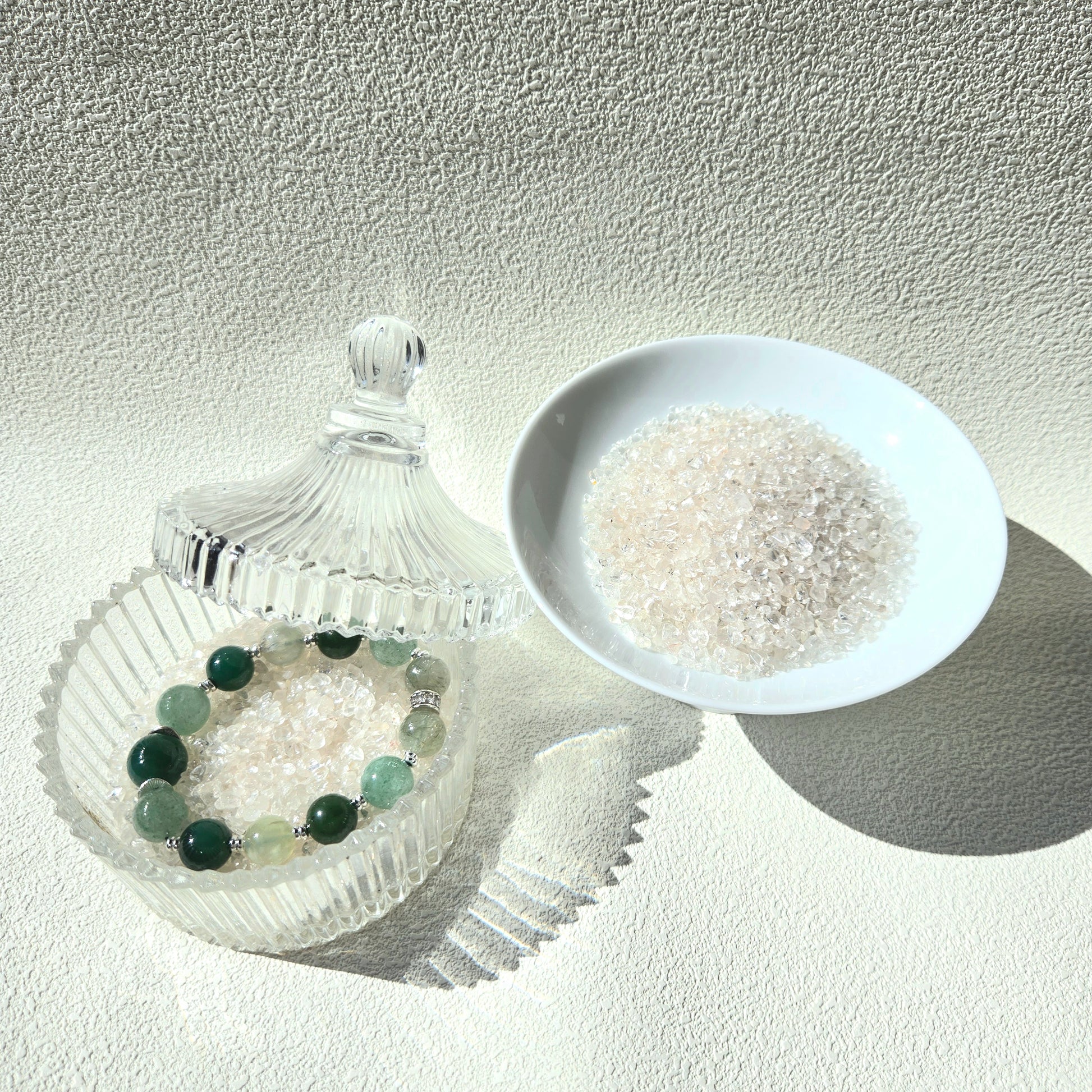Crystal care essentials detail - bracelet resting on white quartz chips for energy purification